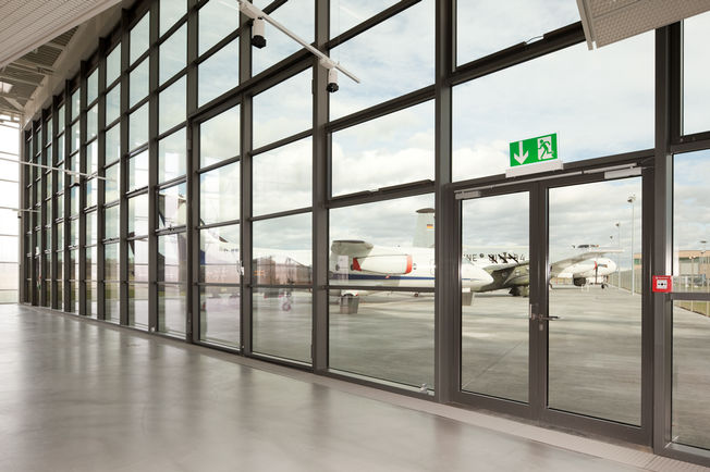 上置滑尺式闭门器 TS 5000 L-ISM, 安装在 Friedrichshafen 的 Dorniermuseum 博物馆中。 上置滑尺式闭门器系统合页异侧，用于双扇门，具有防恐慌功能和顺闭器。