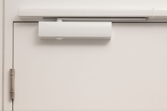 上置滑尺式闭门器 TS 5000 R-ISM TS 5000 R-ISM, 上置滑尺式闭门器系统，用于双扇门，具有顺闭器和烟雾开关，安装在位于 Leonberg 的 GEZE GmbH。