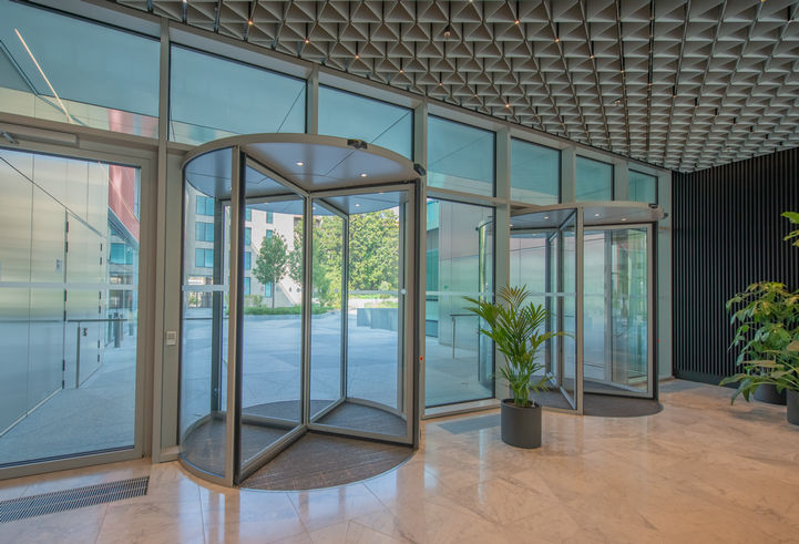 View of a hallway with Revo.PRIME revolving door and plants in the foreground