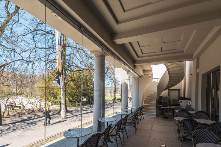 Covered café terrace with glass front, round columns and small tables