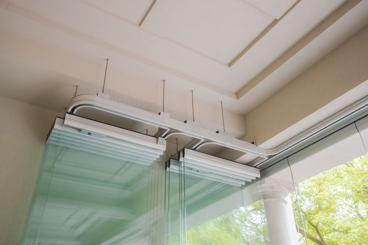 Detailed view of a ceiling track with curved guide for movable glass walls.