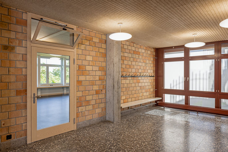 View of the school corridor with a glass door, the upper window of which is tilted open.