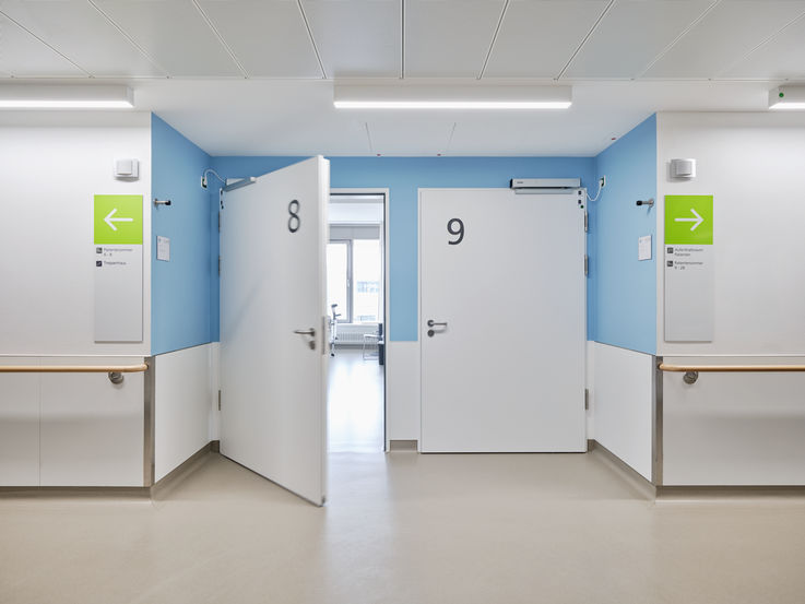 Two wide doors leading to the hospital rooms, one door open and one closed.