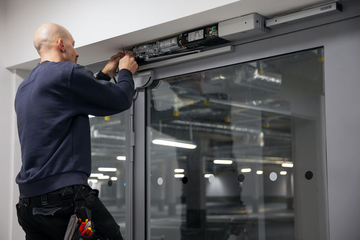 GEZE Service technicians installing a door closer on a large glass door