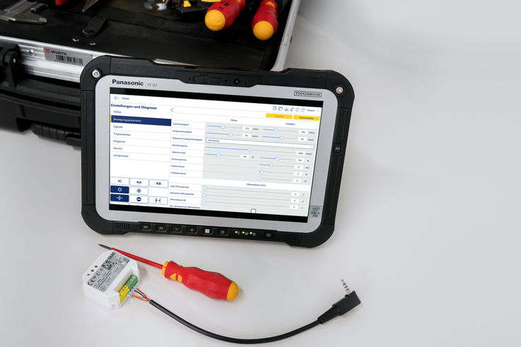 Service-Toughpad mit geöffneter Softwareoberfläche, daneben ein Bluetooth-Modul, Schraubendreher und Werkzeugkoffer im Hintergrund.